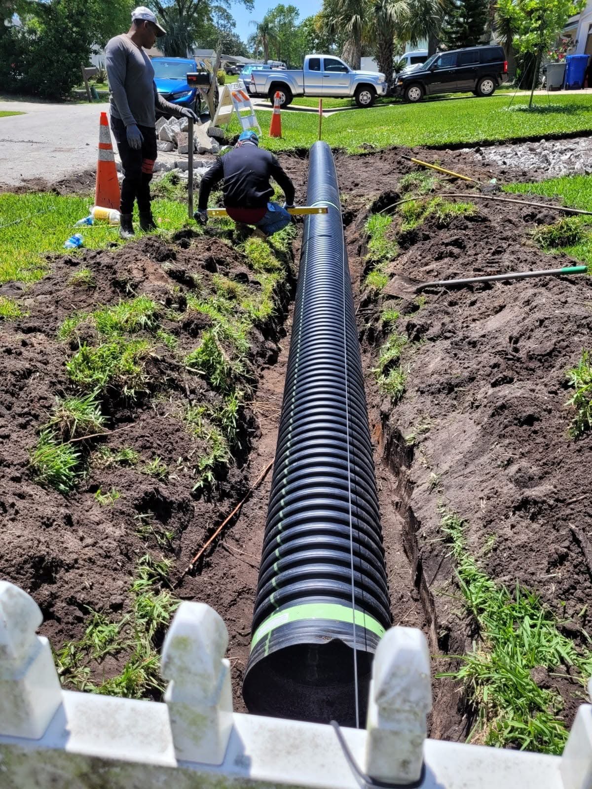 Crew installing drainage pipe in an excavated trench