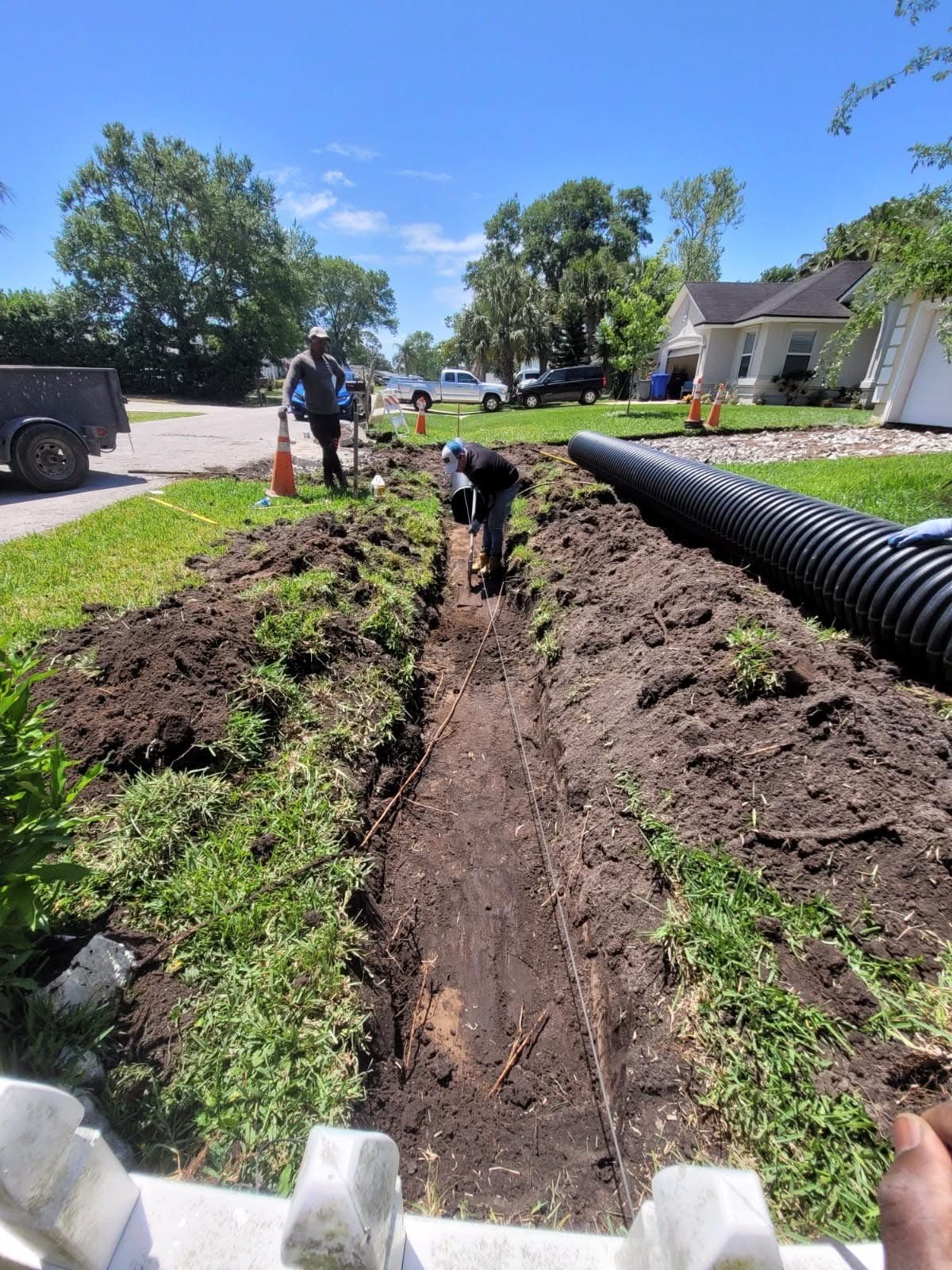 Drainage trench and pipe installation along a residential lawn
